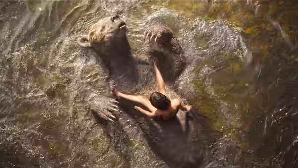 Mowgli (Neel Sethi) clings to Baloo while splashing in a river