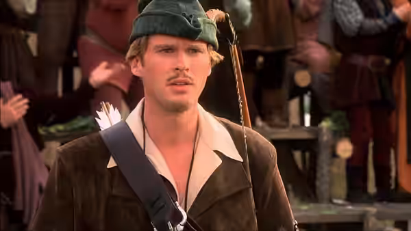 Robin Hood (Cary Elwes) stands alert in green cap and brown tunic