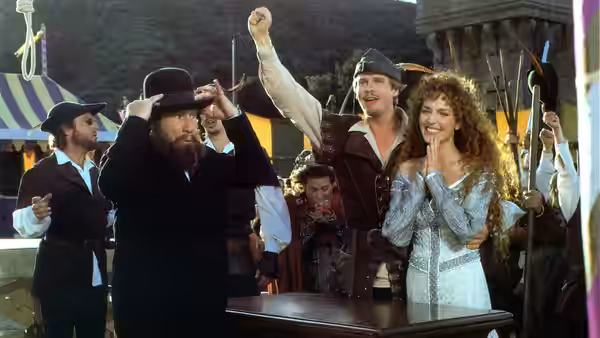 Maid Marian (Amy Yasbeck) smiles beside a man raising his fist at a table