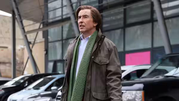 Alan Partridge (Steve Coogan) outside building near parked cars