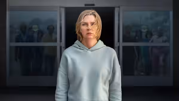 Carol Sturka (Rhea Seehorn) standing before glass doors with people behind her