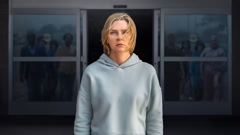 Carol Sturka (Rhea Seehorn) standing before glass doors with people behind her