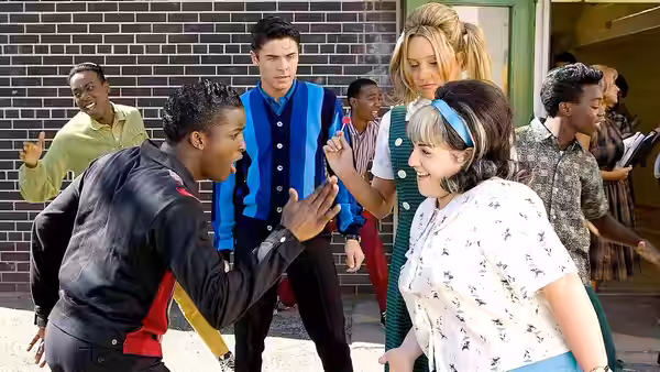 Seaweed (Elijah Kelley) high-fiving Penny Pingleton (Amanda Bynes) outside school