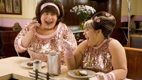 Edna Turnblad (John Travolta) and Tracy Turnblad (Nikki Blonsky) eating cake in a diner