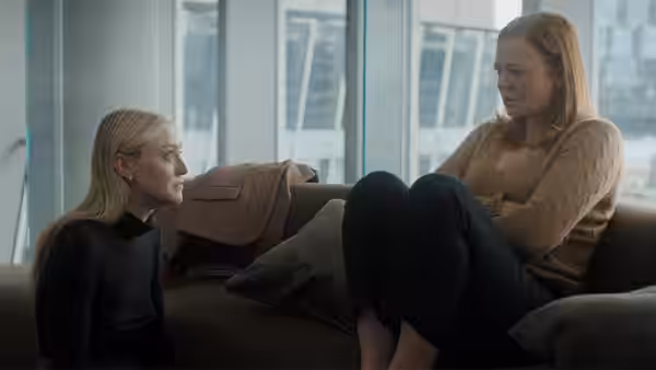 Marissa Irvine (Sarah Snook) and Jenny Kaminski (Dakota Fanning) talking on a living room couch