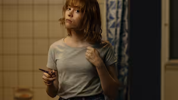 Marissa Irvine (Sarah Snook) standing in a bathroom holding scissors