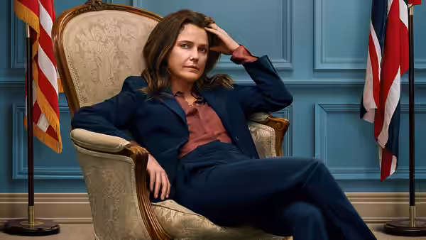 Kate Wyler (Keri Russell) seated in an armchair between two flags
