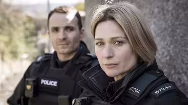 Close-up of a female police officer with a male colleague behind her
