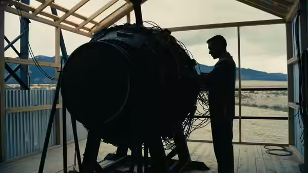 J. Robert Oppenheimer (Cillian Murphy) examining a large spherical device in a desert lab