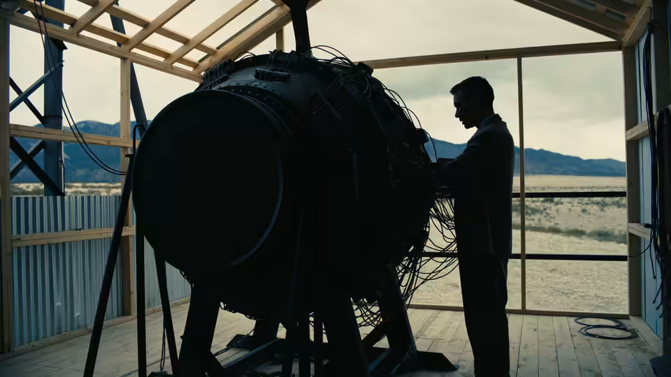 J. Robert Oppenheimer (Cillian Murphy) examining a large spherical device in a desert lab