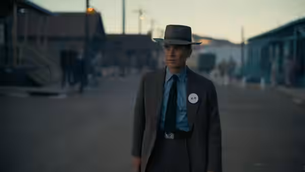J. Robert Oppenheimer (Cillian Murphy) standing on a dirt road between wooden buildings