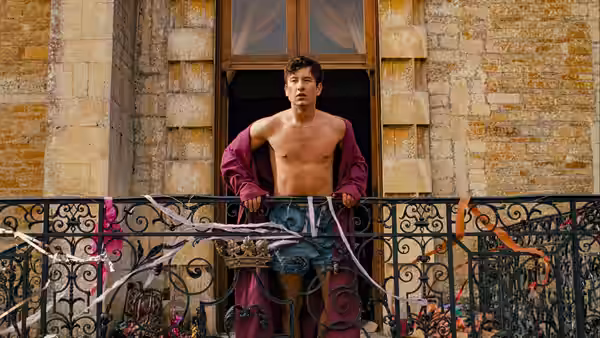 Oliver Quick (Barry Keoghan) standing shirtless on a balcony in a robe