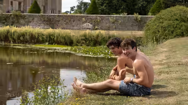 Oliver Quick (Barry Keoghan) and Felix Catton (Jacob Elordi) sitting by a pond