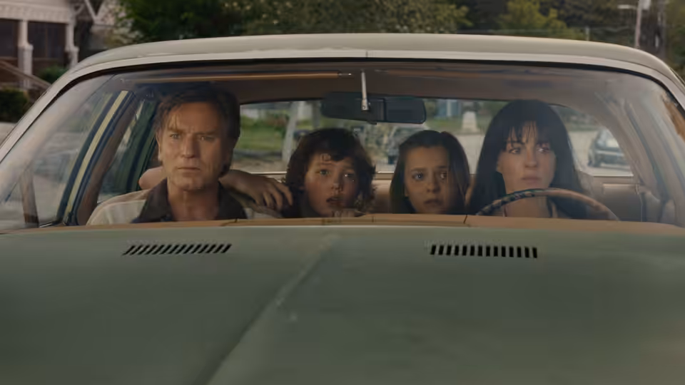 Greg Platt (Ewan McGregor) driving a car with three family members