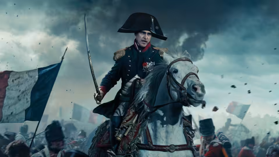 Napoleon Bonaparte (Joaquin Phoenix) riding a white horse into battle