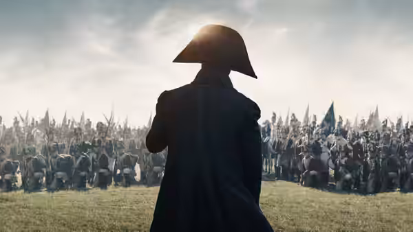 Napoleon Bonaparte standing before his army on a grassy field