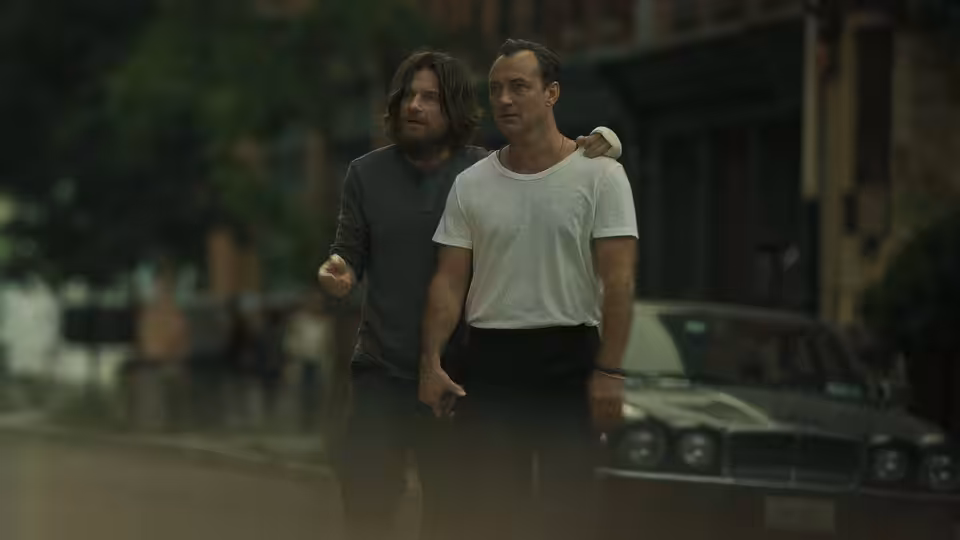 Vince Friedken (Jason Bateman) walking with Jake Friedken (Jude Law) on a wet street