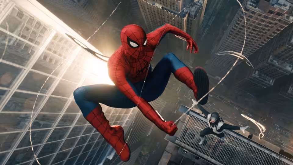 Spider-Man (Tom Holland) swings between tall buildings above a suited figure on a ledge