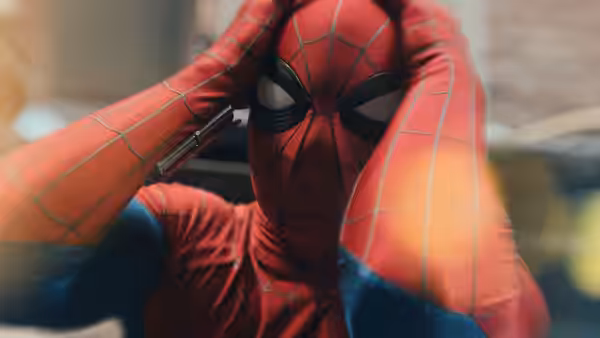 Spider-Man (Tom Holland) clutches his head with both hands in a close-up view