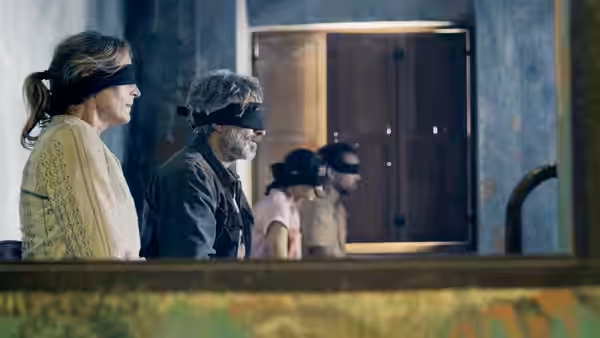 four blindfolded people standing in a line inside a building
