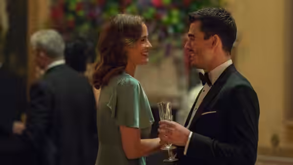 a woman and a man in formal wear smiling at each other indoors