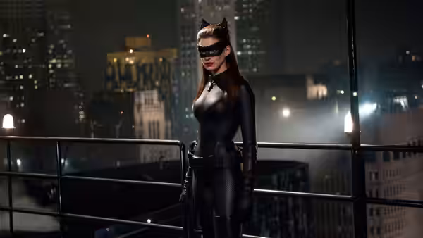Catwoman (Anne Hathaway) stands on a balcony overlooking the city at night