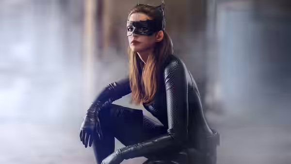 Catwoman (Anne Hathaway) crouches on the ground in a smoky space