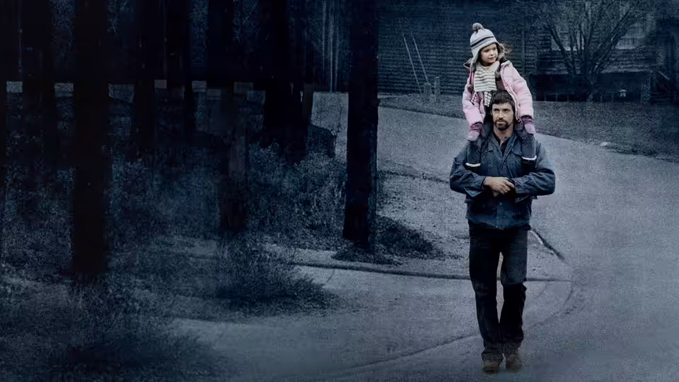 Keller Dover (Hugh Jackman) carrying a young girl on his shoulders down a suburban street