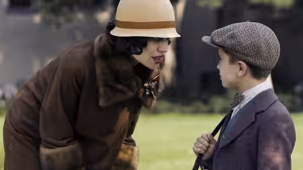 Christine Collins leans close to a boy outdoors and speaks to him