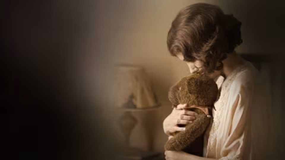 Christine Collins (Angelina Jolie) clutches a teddy bear in a dimly lit room
