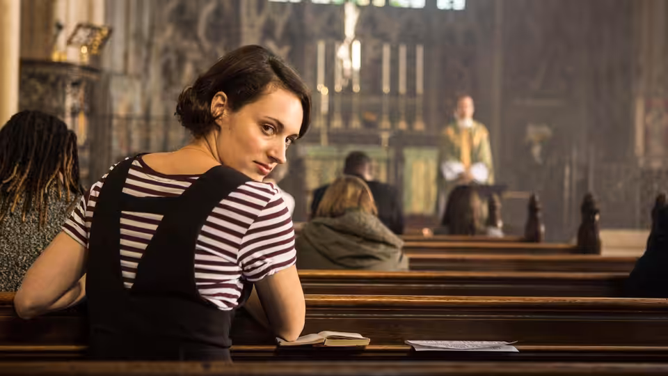 Fleabag (Phoebe Waller-Bridge) turns to look back from a church pew