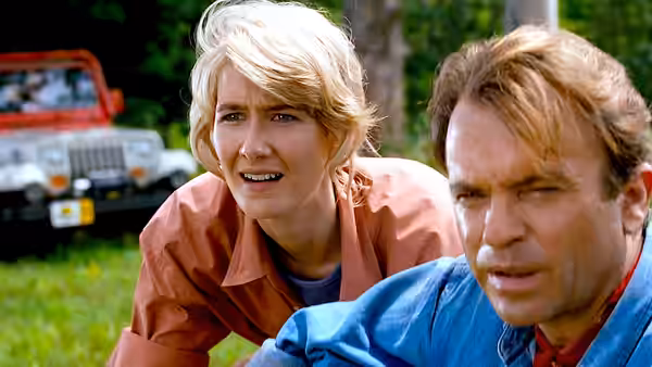 Ellie (Laura Dern) and Malcolm (Jeff Goldblum) crouching with concern near a jeep