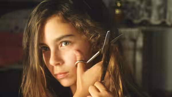 Girl having a lock of hair cut with scissors