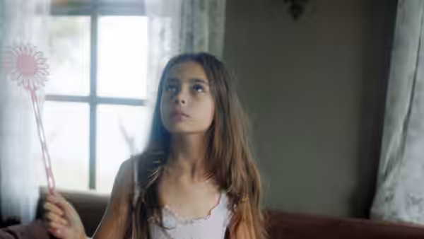 Girl holding a flower wand and looking upwards