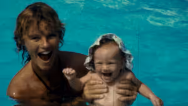 a woman holding a laughing baby in a swimming pool