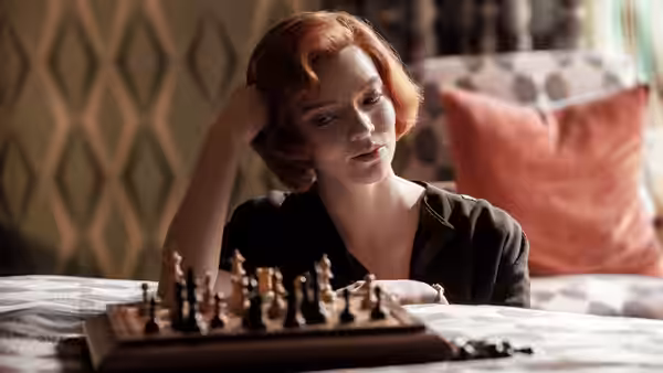 Beth Harmon (Anya Taylor-Joy) resting her head while studying a chessboard