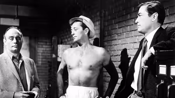 Max Cady (Robert Mitchum), shirtless in a hat, stands between two suited men