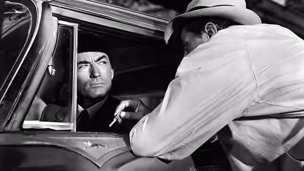 Max Cady (Robert Mitchum) leans into Sam Bowden's car to speak with him