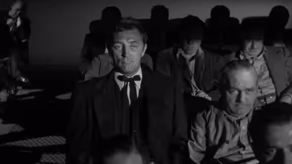 Preacher Harry Powell (Robert Mitchum) seated in an audience at a theater