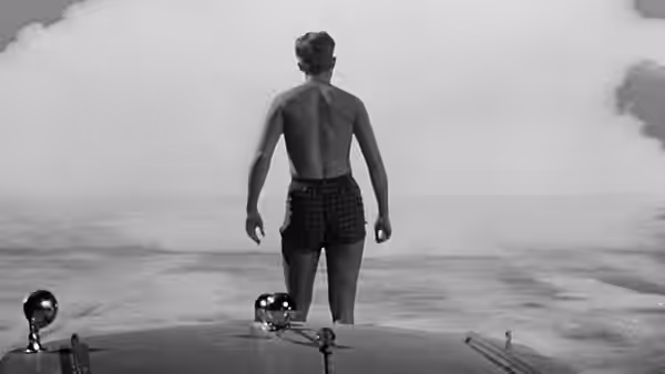 Scott Carey (Grant Williams) stands at the shoreline facing the ocean