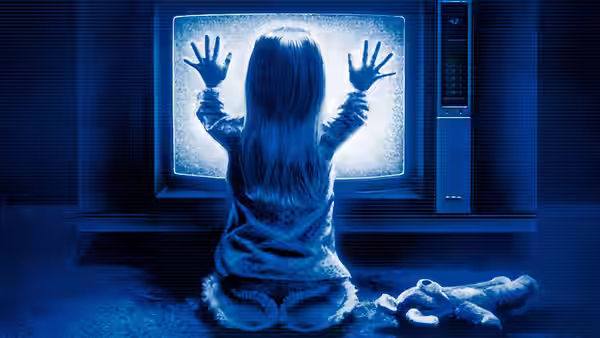 a young girl presses both hands against the glowing screen of a television