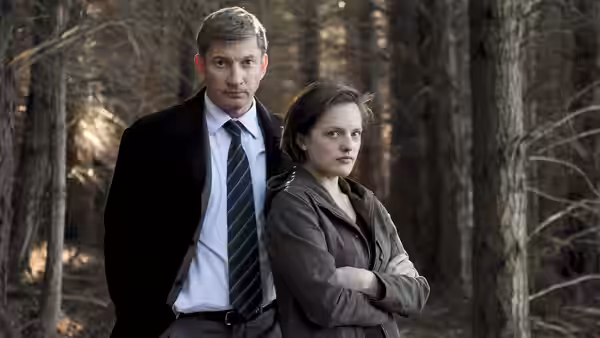 man in suit and Robin Griffin (Elisabeth Moss) standing in woods
