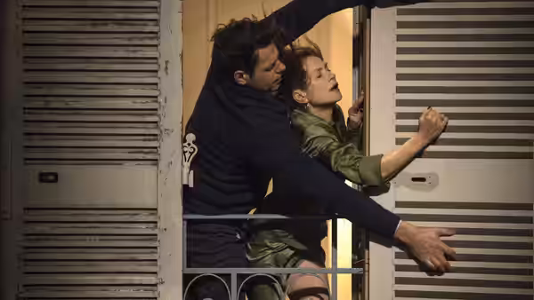Michèle (Isabelle Huppert) struggling with a man on a balcony at night