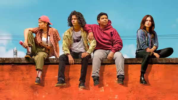 Four young people sitting together on a red wall