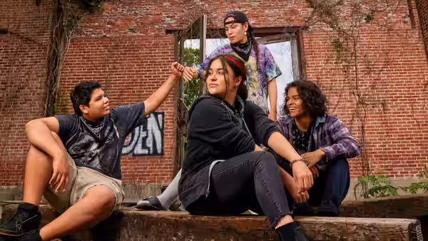 Four friends sitting on steps outside a brick building