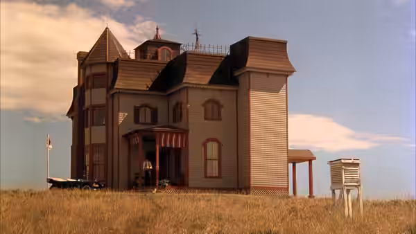 Large wooden house with porch stands in open prairie under blue sky