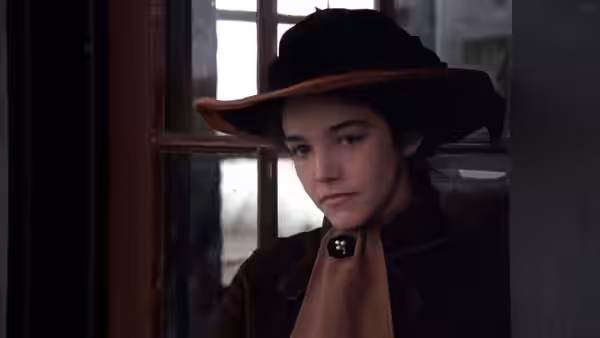 Linda (Linda Manz) gazes out window wearing black hat and coat