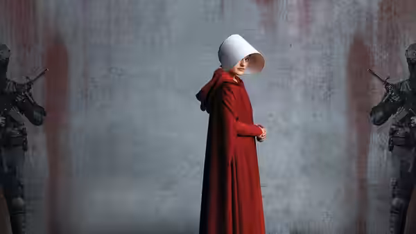 Offred (Elisabeth Moss) standing between two armed guards before a blood-stained wall