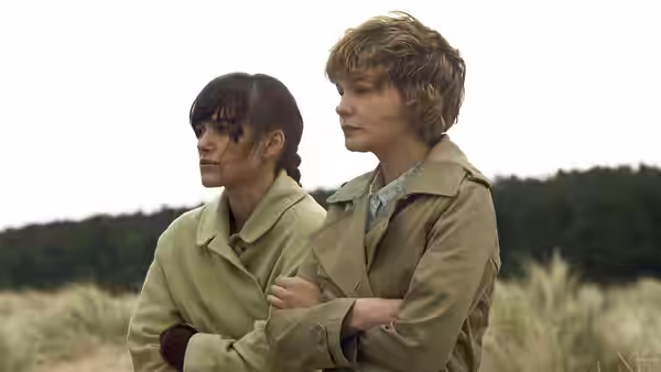 Ruth (Keira Knightley) and Kathy (Carey Mulligan) standing together on a grassy path