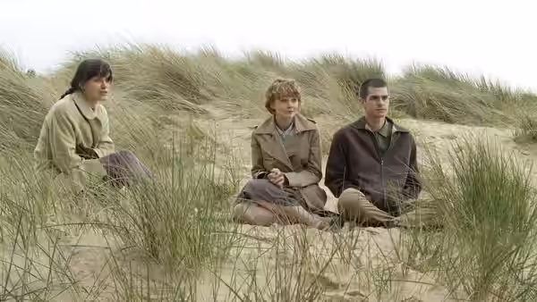 Kathy (Carey Mulligan), Ruth (Keira Knightley) and Tommy (Andrew Garfield) seated in sand dunes